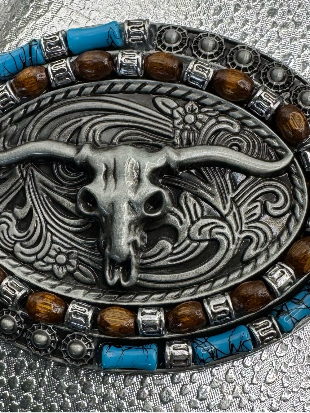 style longhorn skull belt buckle paired with a brown embossed leather strap.
